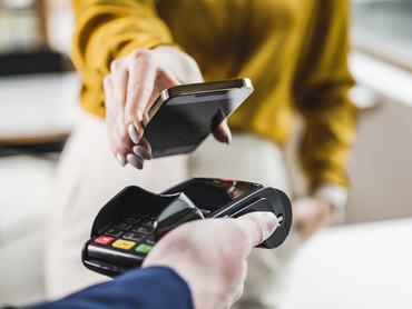 Hand of young businesswoman paying through smart phone