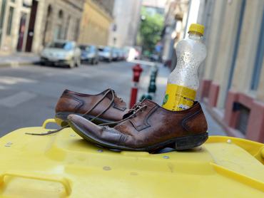 Old leather shoes and an empty bottle stand on a yellow rubbish can in Budapest, Hungary, 06 August 2013. Photo: Jens Kalaene | usage worldwide (Photo by Jens Kalaene/picture alliance via Getty Images)