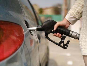 unrecognizable woman using gas pump to add fuel to her car during energy crisis