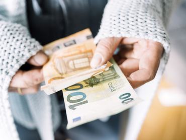 Hands of man wrapped in blanket holding Euro notes