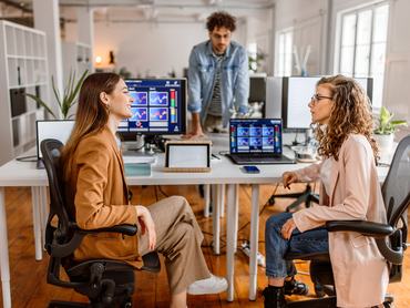 Group of coworkers analysing crypto stock market, using mobile app in the modern office