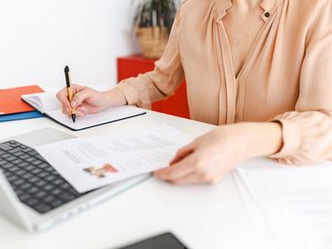 Close up view of female HR recruiter taking notes while reading job applicant resume in the office. Recruitment and hiring concept.