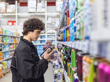 Adolsent boy reading beverage label while shopping in supermarket. unhealthy beverage habits and health risk