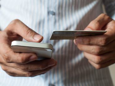 A businessman is buying online using his mobile phone and credit card